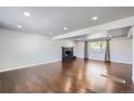 Spacious living room features hardwood floors, a dark brick fireplace, recessed lighting, and a bright window at 7814 W Ontario Pl, Littleton, CO 80128