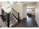 Bright entryway features wood floors, carpeted stairs with dark wood railing, and a view into the living room at 1334 Barberry Trl, Elizabeth, CO 80107