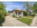 Quaint home with a covered porch, nice lawn, and a long driveway, providing a welcoming curb appeal at 2415 Chase St, Edgewater, CO 80214