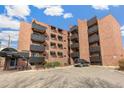 Apartment building featuring a red brick facade, black metal balconies and an on-site parking area at 1833 N Williams St # 201, Denver, CO 80218