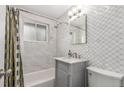 Updated bathroom featuring a shower-tub combo, marble vanity, and decorative tiled walls at 3841 W Quinn Pl, Denver, CO 80236