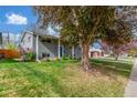 View of the well maintained lawn and garden, the covered entry, and brick facade at 3841 W Quinn Pl, Denver, CO 80236
