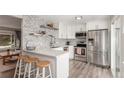 Modern kitchen with white cabinets, stainless steel appliances, quartz countertop, and stylish barstool seating at 3841 W Quinn Pl, Denver, CO 80236