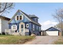 View of a charming two-story blue home with a garage and driveway, showcasing the property's curb appeal at 5103 Quitman St, Denver, CO 80212