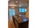 Kitchen island with granite countertops, stainless steel sink and appliances, complemented by hardwood floors at 23014 Milford Ln, Parker, CO 80138