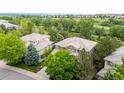 An aerial view of a brown two-story home surrounded by lush greenery and neighboring houses in a residential neighborhood at 3126 Aspen Creek Dr, Highlands Ranch, CO 80129