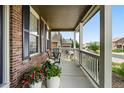 Cozy front porch features brick accents, outdoor seating, and charming decor at 11985 Singing Winds St, Parker, CO 80138