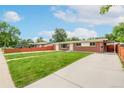 A cozy single-story brick home with a nice driveway, and well-maintained lawn under a bright sunny sky at 3216 Revere St, Aurora, CO 80011