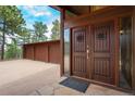 Inviting front entrance with a massive wooden door, sidelight window, and extra deep three-car garage at 5565 Osage Way, Larkspur, CO 80118
