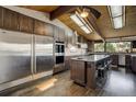Gourmet kitchen featuring stainless steel appliances, center island, custom cabinets, and wood paneled ceiling at 5565 Osage Way, Larkspur, CO 80118
