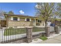 Inviting brick home with a manicured lawn, black metal fence and bench near the front door at 12333 Edwards Pl, Denver, CO 80239