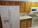 Kitchen featuring white appliances, including a refrigerator and microwave, complemented by wooden cabinetry at 2907 S Upham St, Denver, CO 80227