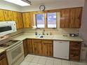 Well-lit kitchen with warm wood cabinets, white appliances, and a view from the window over the sink at 2907 S Upham St, Denver, CO 80227