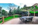 Outdoor patio with a dining table and umbrella overlooking a lush green backyard at 76 Buckthorn Dr, Littleton, CO 80127