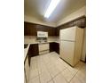 Traditional kitchen featuring tile flooring, a white refrigerator, microwave, range, and wood cabinetry at 12973 E Cornell Ave, Aurora, CO 80014