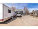 Exterior shot of the property with a Quonset-style garage, recreational vehicles, and ample parking space at 410 Goodrich Ave, Platteville, CO 80651