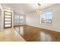 Bright, open-concept living room features gleaming hardwood floors and abundant natural light from large windows at 13601 Krameria St, Thornton, CO 80602