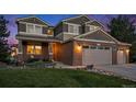 Inviting two-story brick home with a three-car garage, illuminated in the twilight at 7624 Russell Ct, Arvada, CO 80007