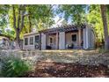 One-story home with xeriscaping, covered porch with swing, and lush trees at 4921 Beach Ct, Denver, CO 80221