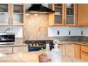 Close-up of the kitchen's granite countertops, gas cooktop, microwave, and wooden cabinets with glass fronts at 1438 Little Raven St # 301, Denver, CO 80202