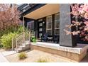 Inviting covered front porch with seating, stylish black exterior, and lush landscaping with beautiful trees in bloom at 2777 Ironton St, Denver, CO 80238