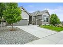 A home with great curb appeal has a well-maintained lawn and a convenient two-car attached garage with stone accents at 16256 Ute Peak Way, Broomfield, CO 80023