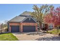 Attached three-car garage featuring dark gray doors and a concrete driveway at 404 Yarrow Pl, Castle Pines, CO 80108