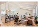 Inviting living room and kitchen area with vaulted ceiling, wood floors, and modern decor at 6472 W Brittany Pl, Littleton, CO 80123
