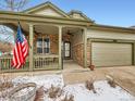 Close-up of a home's entrance, featuring a covered porch with brick detail and an American flag at 23236 Chapel Hill Pl, Parker, CO 80138