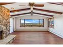 Bright living room featuring exposed beams, hardwood floors, and a stone fireplace at 14091 W Exposition Dr, Lakewood, CO 80228