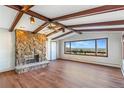 Bright living room with wood floors, beamed ceilings, a stone fireplace, and mountain view windows at 14091 W Exposition Dr, Lakewood, CO 80228