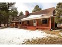 Inviting single-story home featuring a covered porch with red railings, complemented by a mature tree line at 17720 Canterbury Dr, Monument, CO 80132