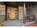 Inviting front porch with stone accents, wood door, stylish table and chairs for relaxing at 1423 Belford Ct, Evergreen, CO 80439