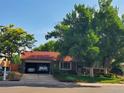 Charming home exterior featuring a red roof, attached garage, complemented by lush green trees and a well-maintained lawn at 14867 E Harvard Ave, Aurora, CO 80014