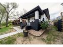 Angle view of a charming home featuring a covered porch, black and white brick, and landscaped garden with lilacs at 4267 Federal Blvd, Denver, CO 80211
