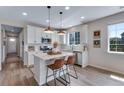 Bright kitchen boasting white cabinets, an island with bar seating, and hardwood floors at 944 Alpine Ridge St, Erie, CO 80516