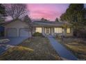 Charming ranch-style home with a well-manicured lawn and two-car garage silhouetted by twilight sky at 5749 S Lansing Way, Englewood, CO 80111