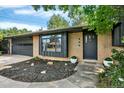 Charming brick home with a black front door, updated landscaping, and well-manicured lawn at 400 S Hoyt St, Lakewood, CO 80226