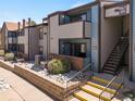 Inviting condo exterior with private patios, stone landscaping, stairway access, and building signage at 12053 E Harvard Ave # 107, Aurora, CO 80014