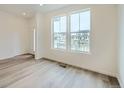 Bright living room with wood floors and large windows showing the neighborhood outside at 700 N Bently St, Watkins, CO 80137