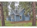 Back exterior view of a quaint two-story home featuring wood siding and mature trees at 7957 Elm St, Louviers, CO 80131