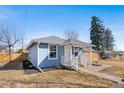 Quaint blue home with a covered front porch and well-maintained yard on a sunny day at 4846 Knox Ct, Denver, CO 80221