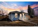Quaint blue home with a covered front porch and well-maintained yard at dusk at 4846 Knox Ct, Denver, CO 80221