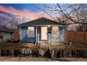 Charming blue home with a white picket fence and a cozy front porch at dusk at 4846 Knox Ct, Denver, CO 80221