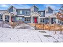 Charming blue townhomes with red doors and white trim, surrounded by a rustic wooden fence in winter at 6211 W 28Th Ct, Wheat Ridge, CO 80214