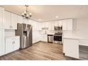 Bright kitchen with white cabinetry, stainless steel appliances, chandelier, and wood flooring at 9300 E Center Ave # 3A, Denver, CO 80247