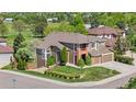 Beautifully landscaped home with manicured lawn, mature trees, and charming architectural details at 8922 S Tuscany Ln, Highlands Ranch, CO 80130