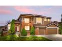 Inviting home featuring warm exterior lighting, manicured lawn, and charming architectural details at 8922 S Tuscany Ln, Highlands Ranch, CO 80130