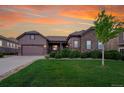 Charming home featuring a stone facade, covered porch, manicured lawn and a two-car garage beneath an orange sunset at 27615 E Moraine Dr, Aurora, CO 80016