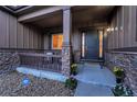 Welcoming front porch with stone accents, a dark-stained front door, and attractive landscaping at 27615 E Moraine Dr, Aurora, CO 80016